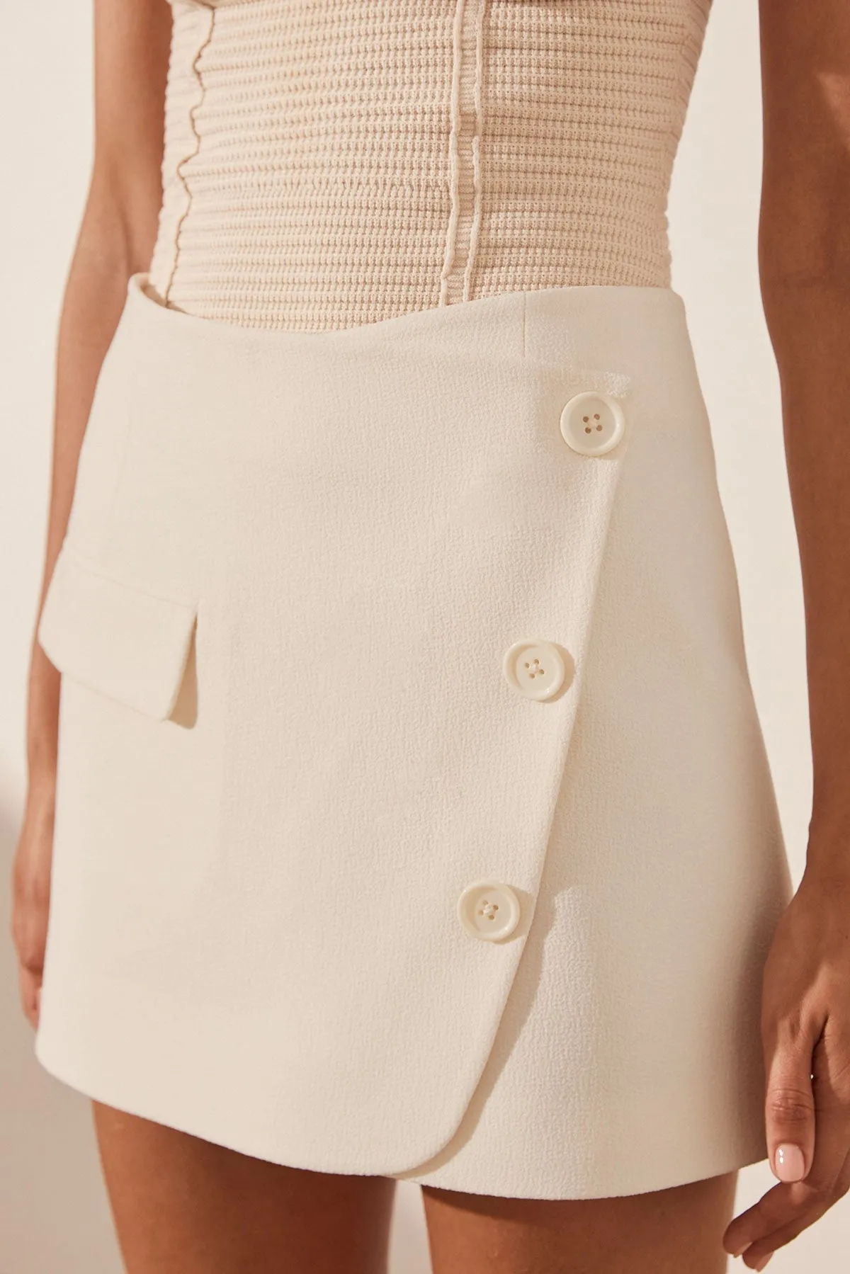 AMURA ASYMMETRICAL BUTTON MINI SKIRT - CREAM